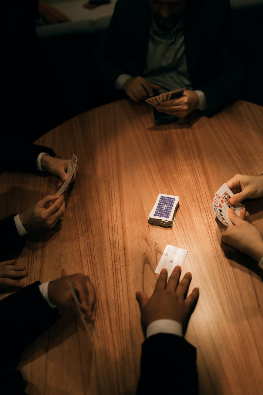 group playing cards at wooden table in dim light